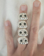 A lifestyle view of four 925 silver Ploop seal rings stacked on a finger, crafted by Dzoo for Rainbow Tears.