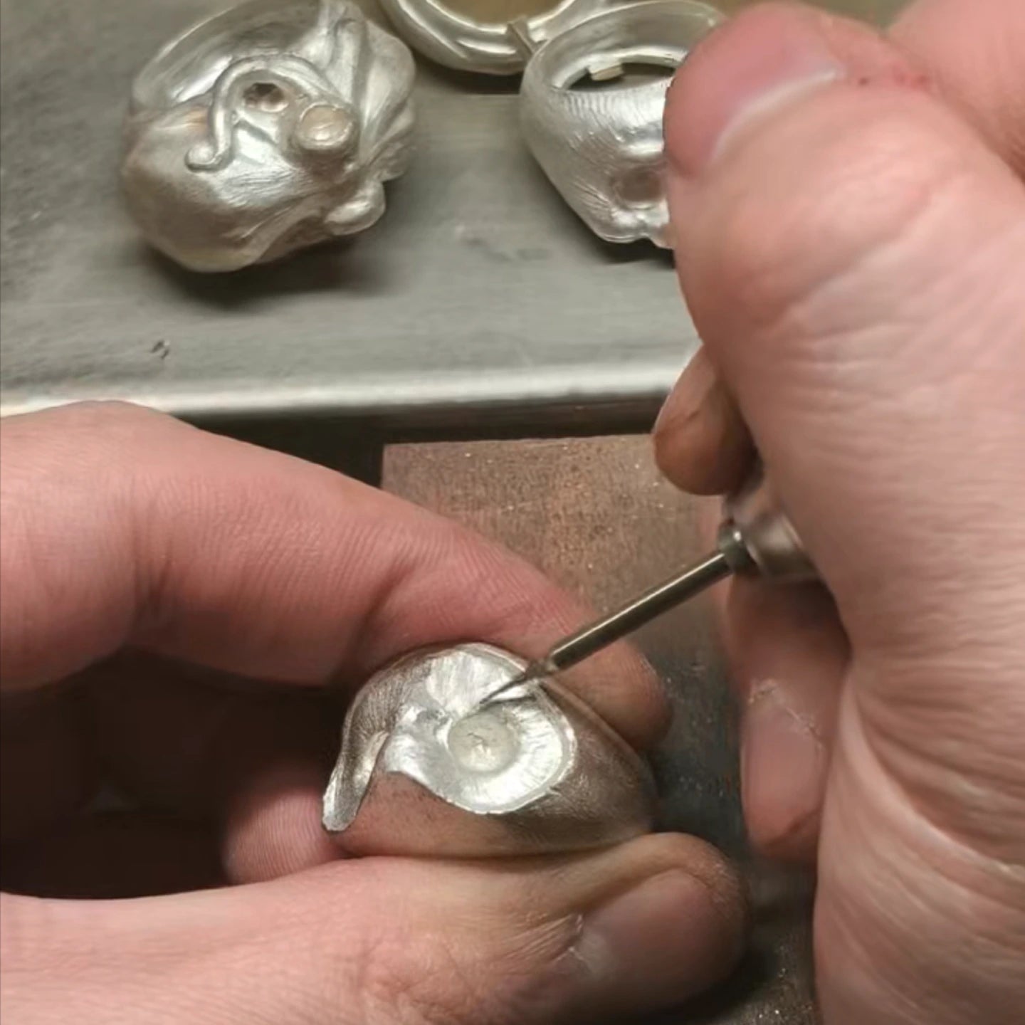 Jeweler manually refining the organic texture of a 990 fine silver owl ring, showcasing unique designer craftsmanship.