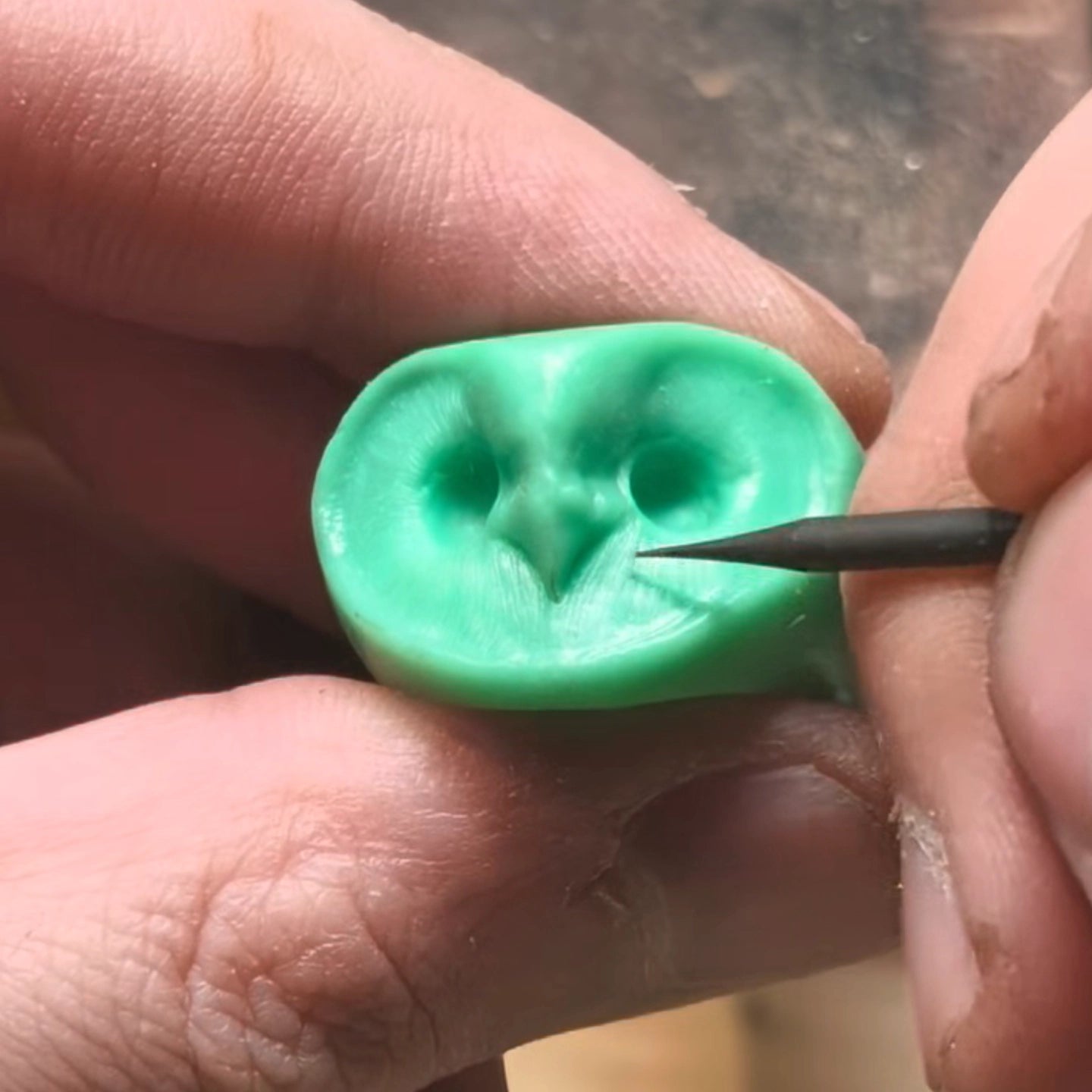 Jeweler refining an owl ring wax model, showcasing the handcrafted process of unique designer jewelry.