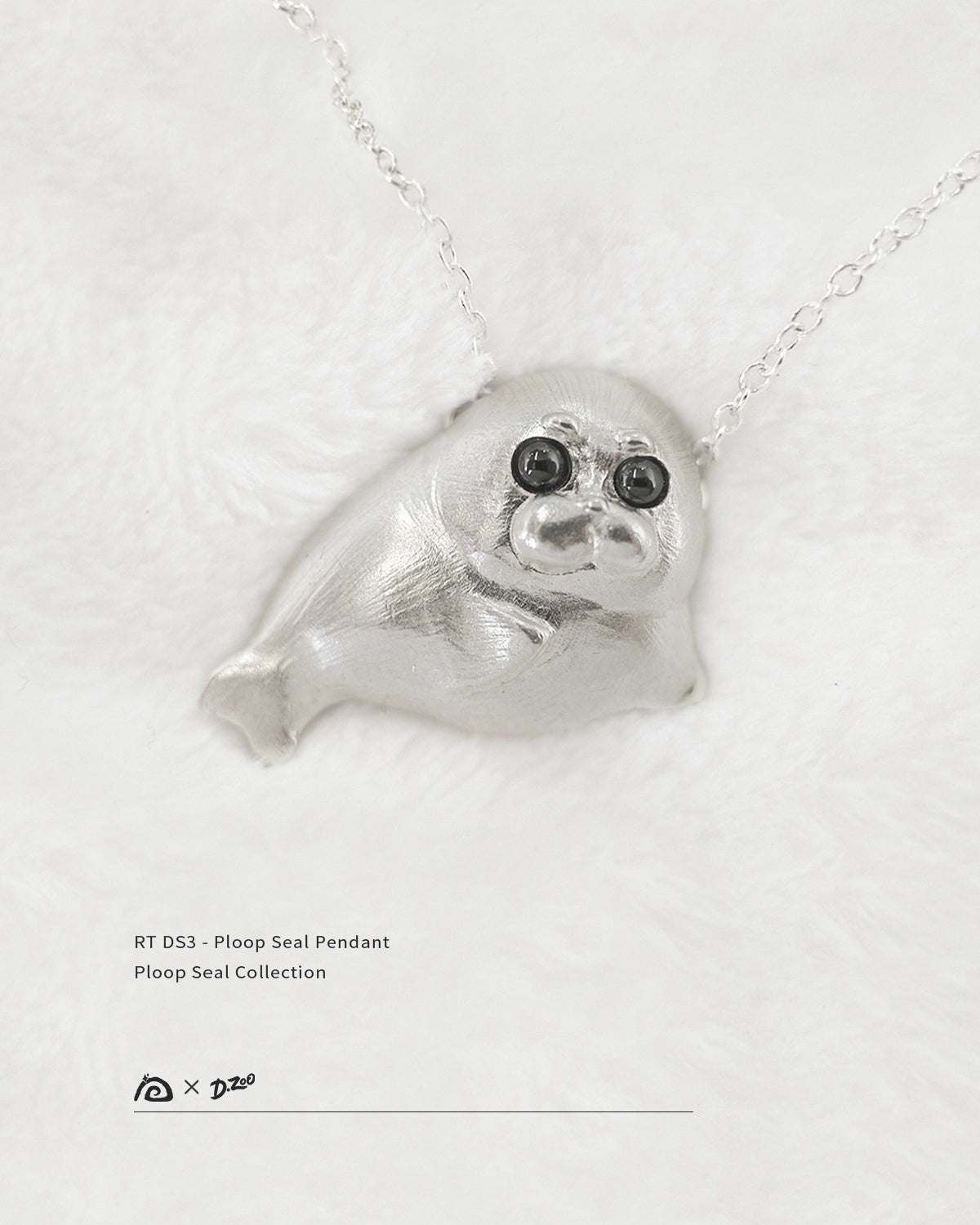 Front view of 925 sterling silver Ploop seal pendant with black cubic zirconia eyes on white velvet, by Dzoo, at Rainbow Tears.