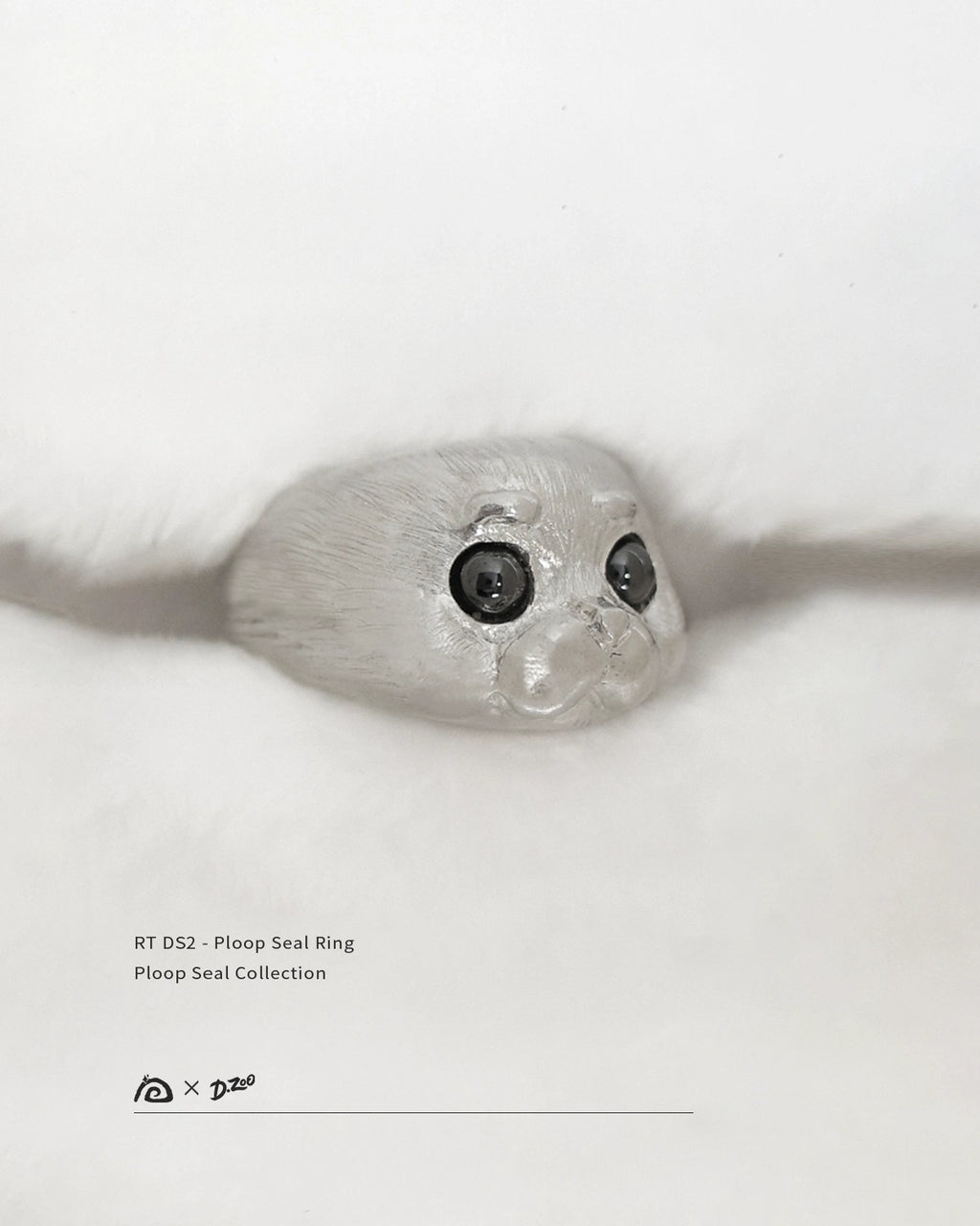 A 45-degree view of the 925 sterling silver Ploop seal ring on a white blanket, by Dzoo, available at Rainbow Tears.
