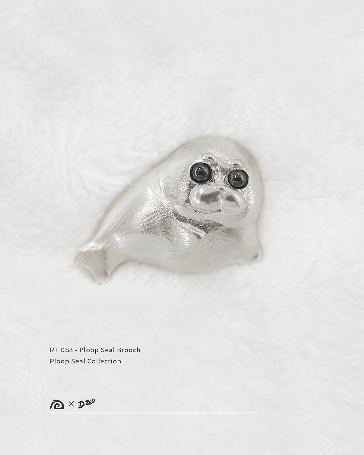 Front view of 925 sterling silver Ploop seal brooch with black cubic zirconia eyes on white velvet, by Dzoo, at Rainbow Tears.
