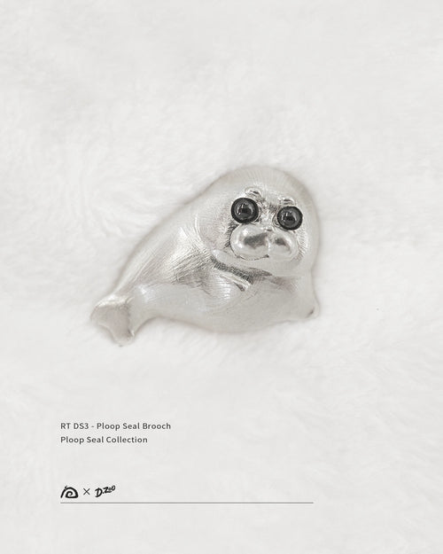 Front view of 925 sterling silver Ploop seal brooch with black cubic zirconia eyes on white velvet, by Dzoo, at Rainbow Tears.