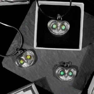 Three owl necklaces with opal eyes, including one yellow-tone opal and two blue-tone opals, displayed with a hand-drawn jewelry box.