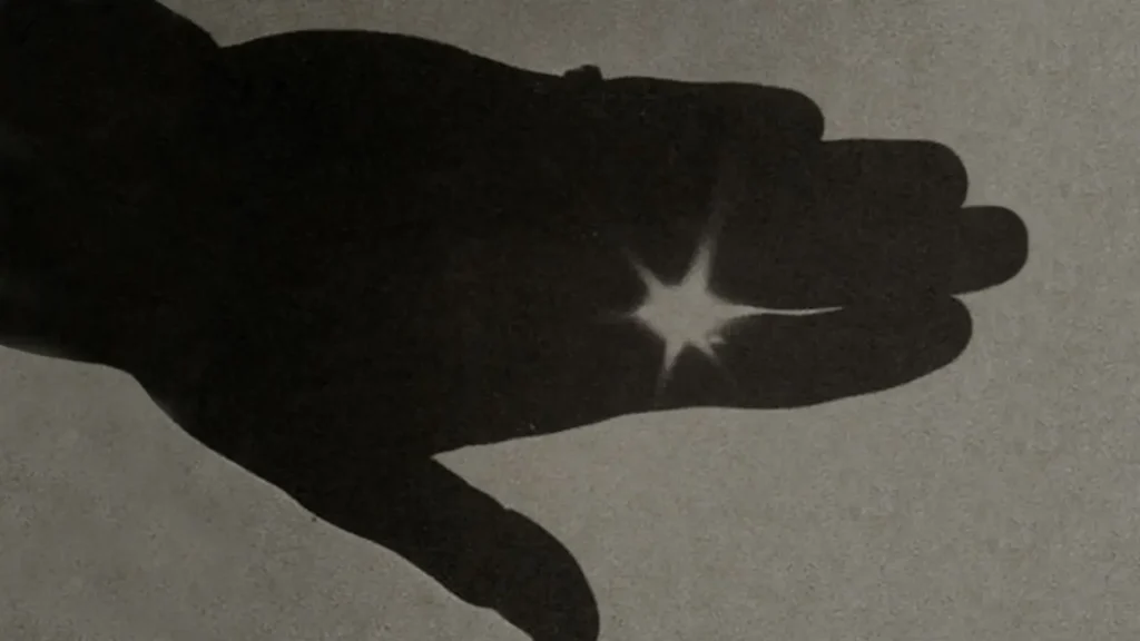 Silhouette of a black hand with light passing through the fingers, representing the hidden talent of designers in Rainbow Tears' story.