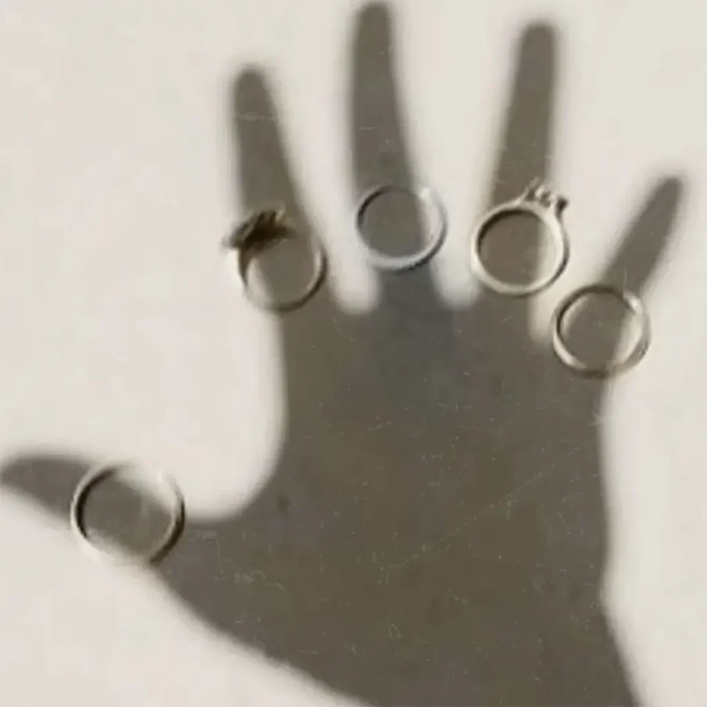 Shadow of an open hand with five rings on its fingers, symbolizing individuality and collaboration under Rainbow Tears' twin missions.