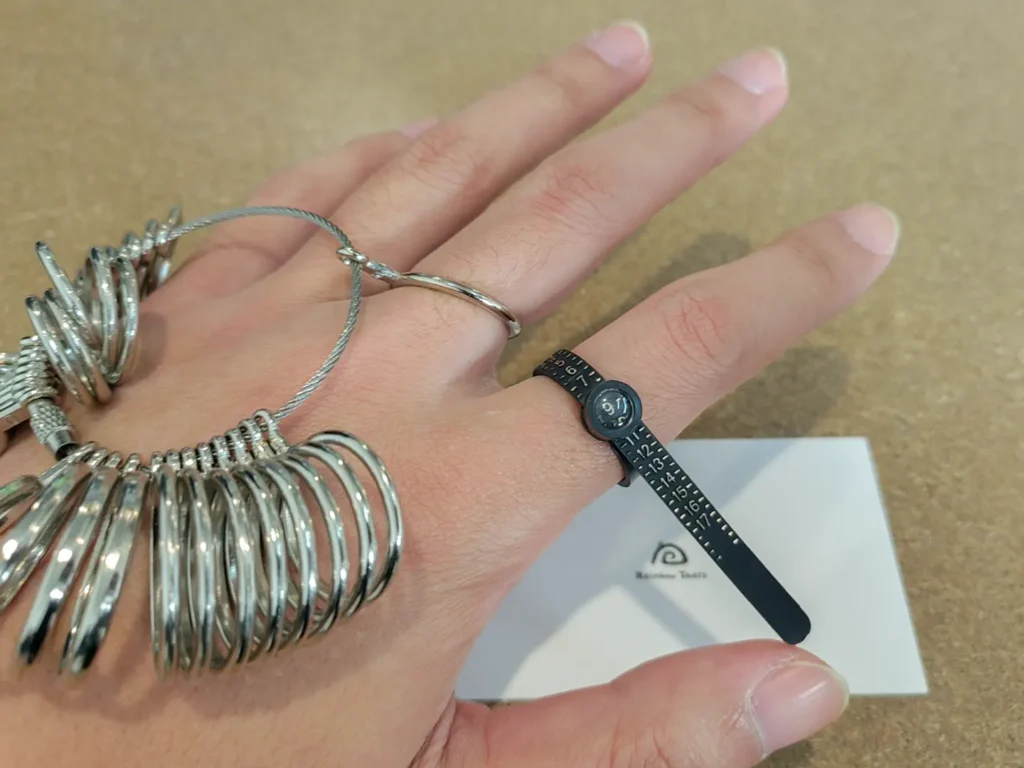 Ring size being measured using two different sizing tools on fingers