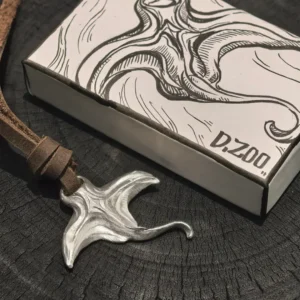 A silver sea-inspired pendant tied with a leather cord beside a hand-painted jewelry box