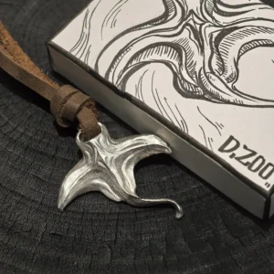 Manta ray necklace with leather cord placed beside a hand-painted jewelry box