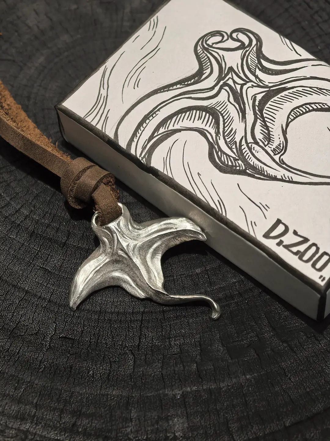 Manta ray necklace with leather cord placed beside a hand-painted jewelry box