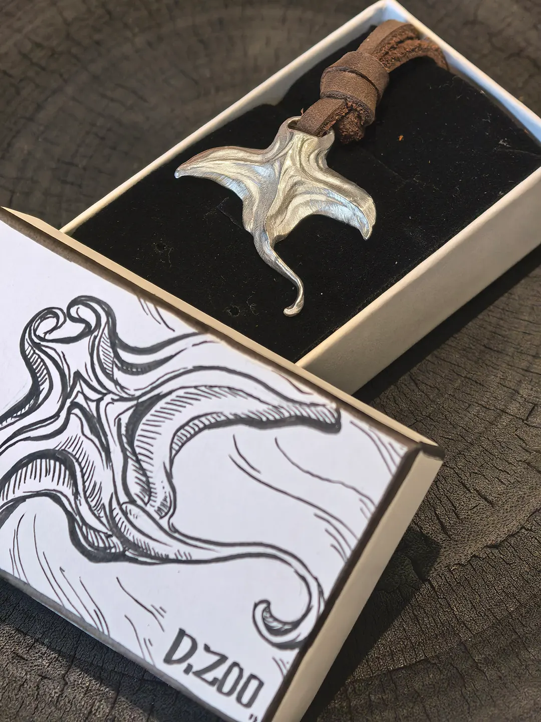 Manta ray necklace with leather cord placed inside a hand-painted jewelry box