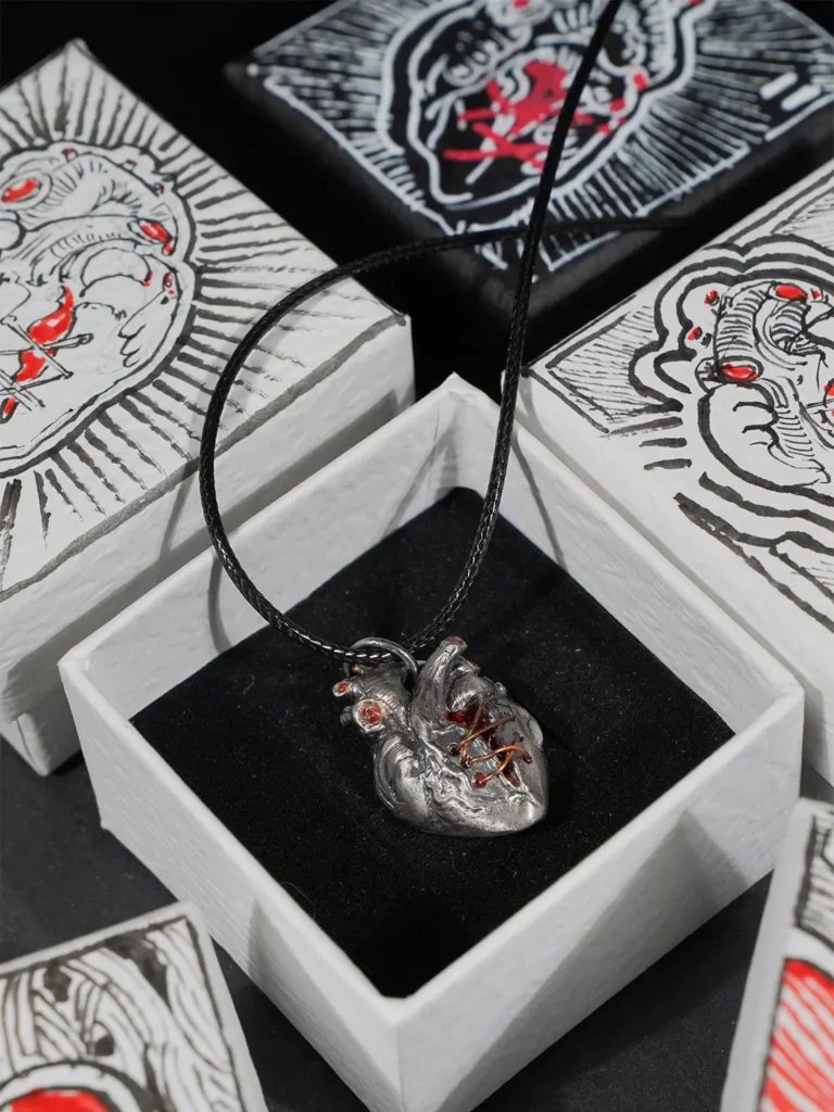 A 925 sterling silver broken heart pendant displayed in its original packaging, surrounded by a curated collection of uniquely decorated, hand-painted gift boxes in various artistic patterns.