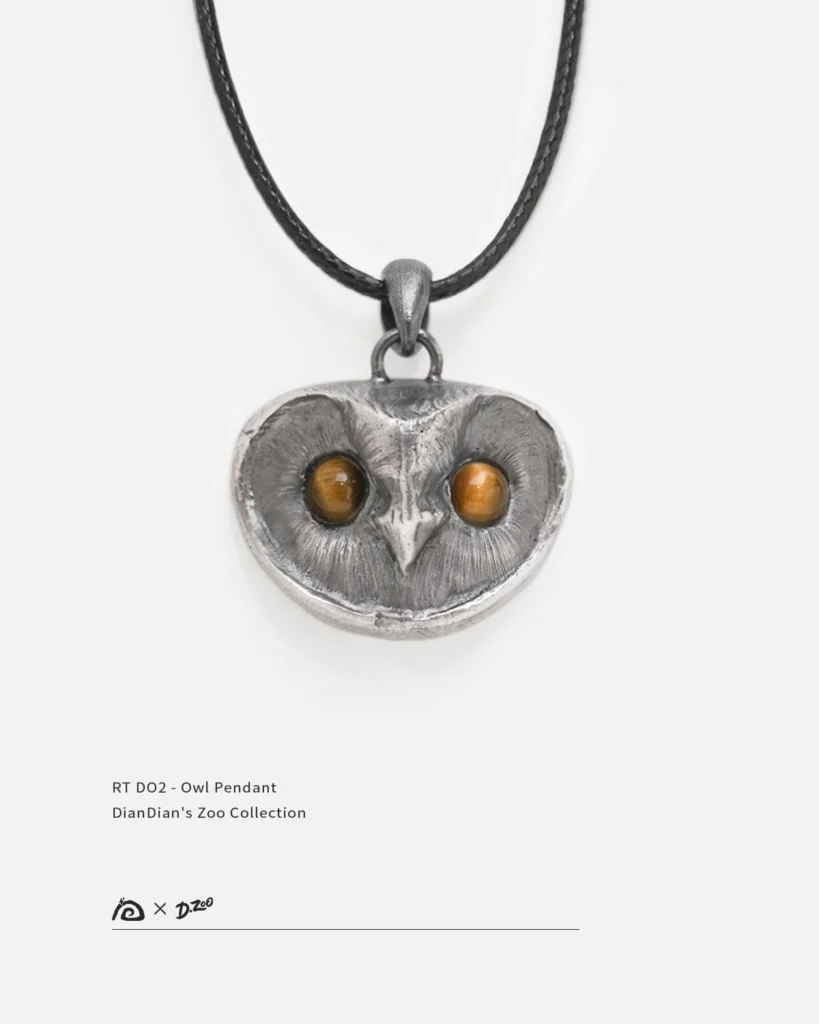 Front view of a sterling silver owl pendant with tiger's eye stone eyes on a white background
