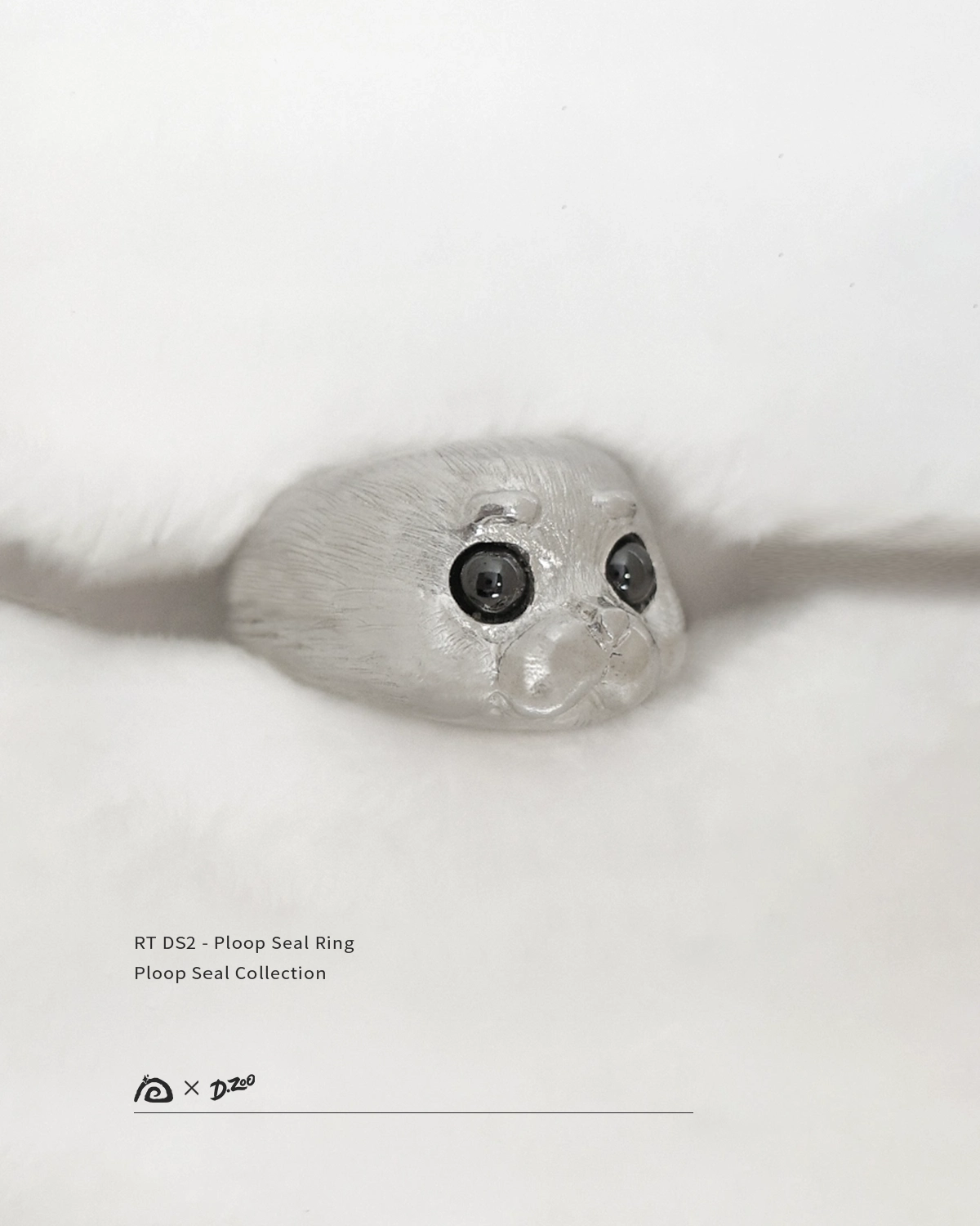The pure silver Ploop seal ring is placed on a white blanket at a 45-degree angle.
