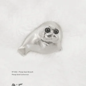 Front view of the pure silver Ploop seal brooch placed on white velvet