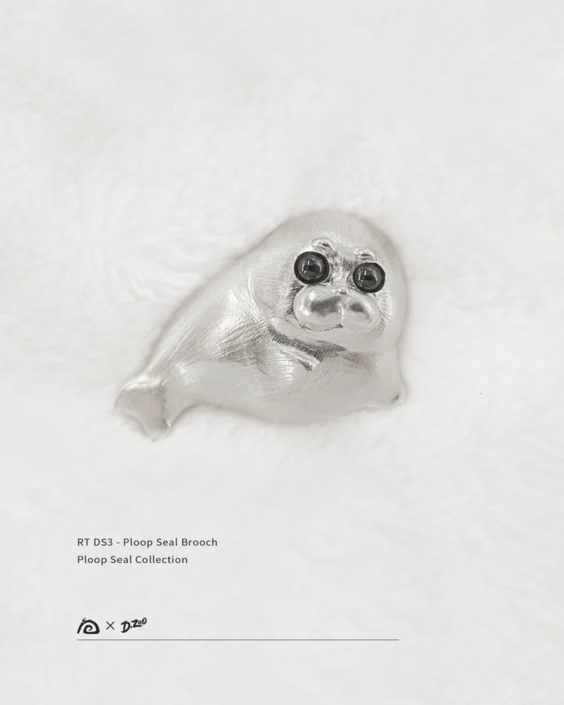 Front view of the pure silver Ploop seal brooch placed on white velvet