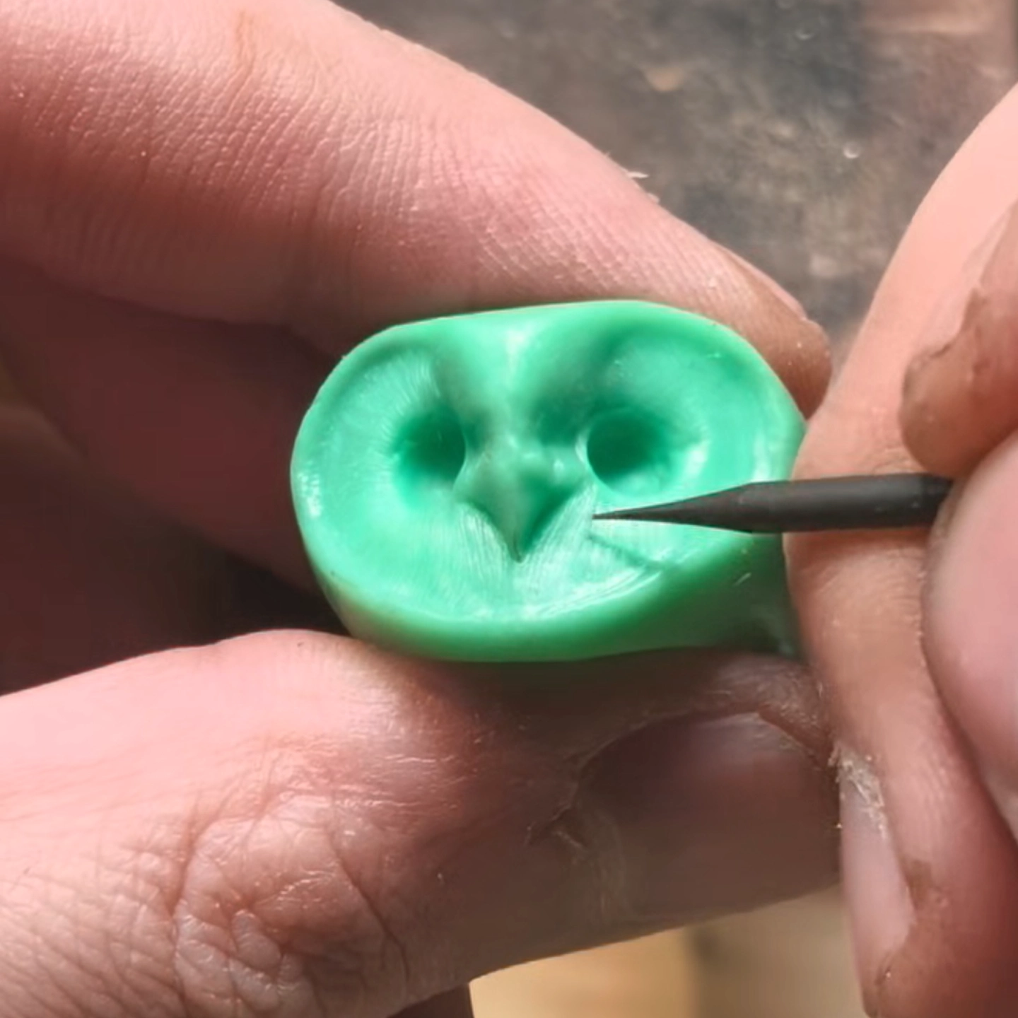 Jeweler refining an owl ring wax model during handcrafted jewelry making process