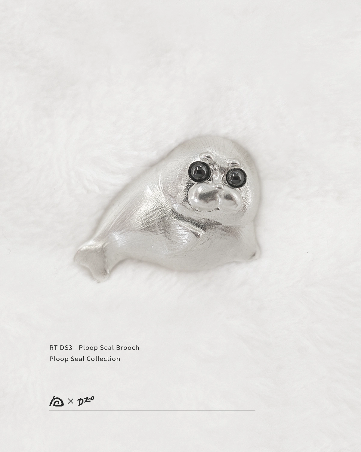 Front view of the pure silver Ploop seal brooch placed on white velvet