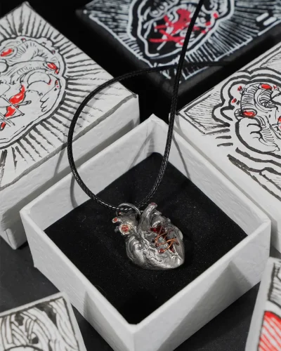A 925 sterling silver broken heart pendant displayed in its original packaging, surrounded by a curated collection of uniquely decorated, hand-painted gift boxes in various artistic patterns.