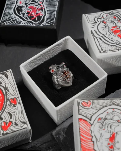 Display a pure silver broken heart ring, featuring a stitched design, securely placed in the central jewelry box. Surrounding it are several closed, hand-painted unique jewelry boxes, each adorned with exquisite artistic patterns.